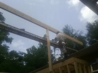 Carpenter setting a ridge beam over a new addition frame — Ice Dam Removal by Roofing Brothers in Durhamville