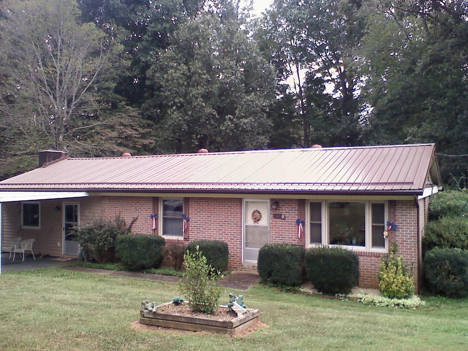 Bronze metal roof on a brick ranch home with a carport in Durhamville