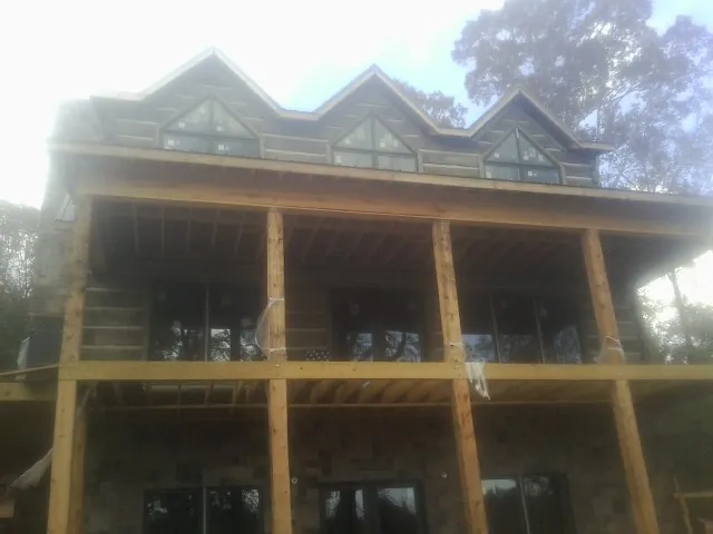 Dormers and porch framing on a large log home under construction — Roof Coating work by our crew in Durhamville