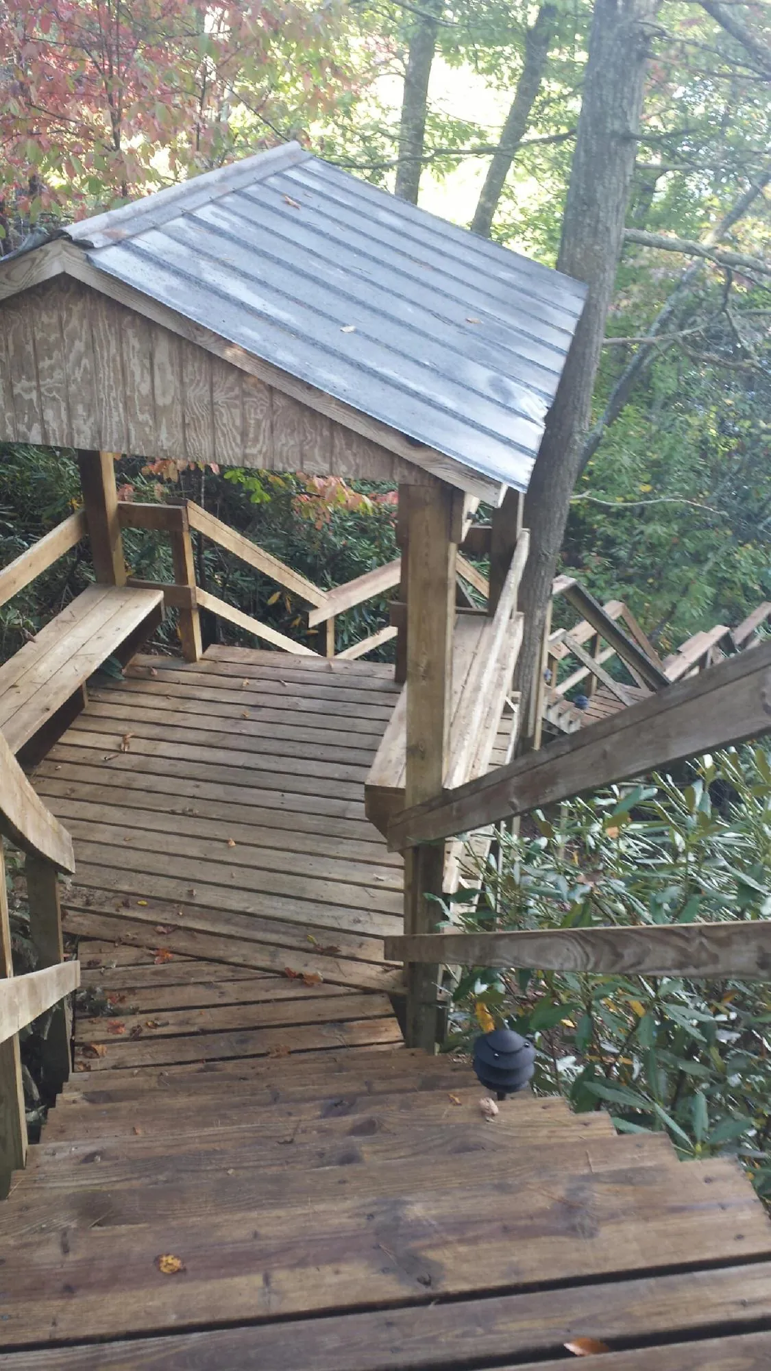 Metal roofed shelter over wooden steps on a wooded walkway — Skylight Repair & Installation work by our crew in Durhamville