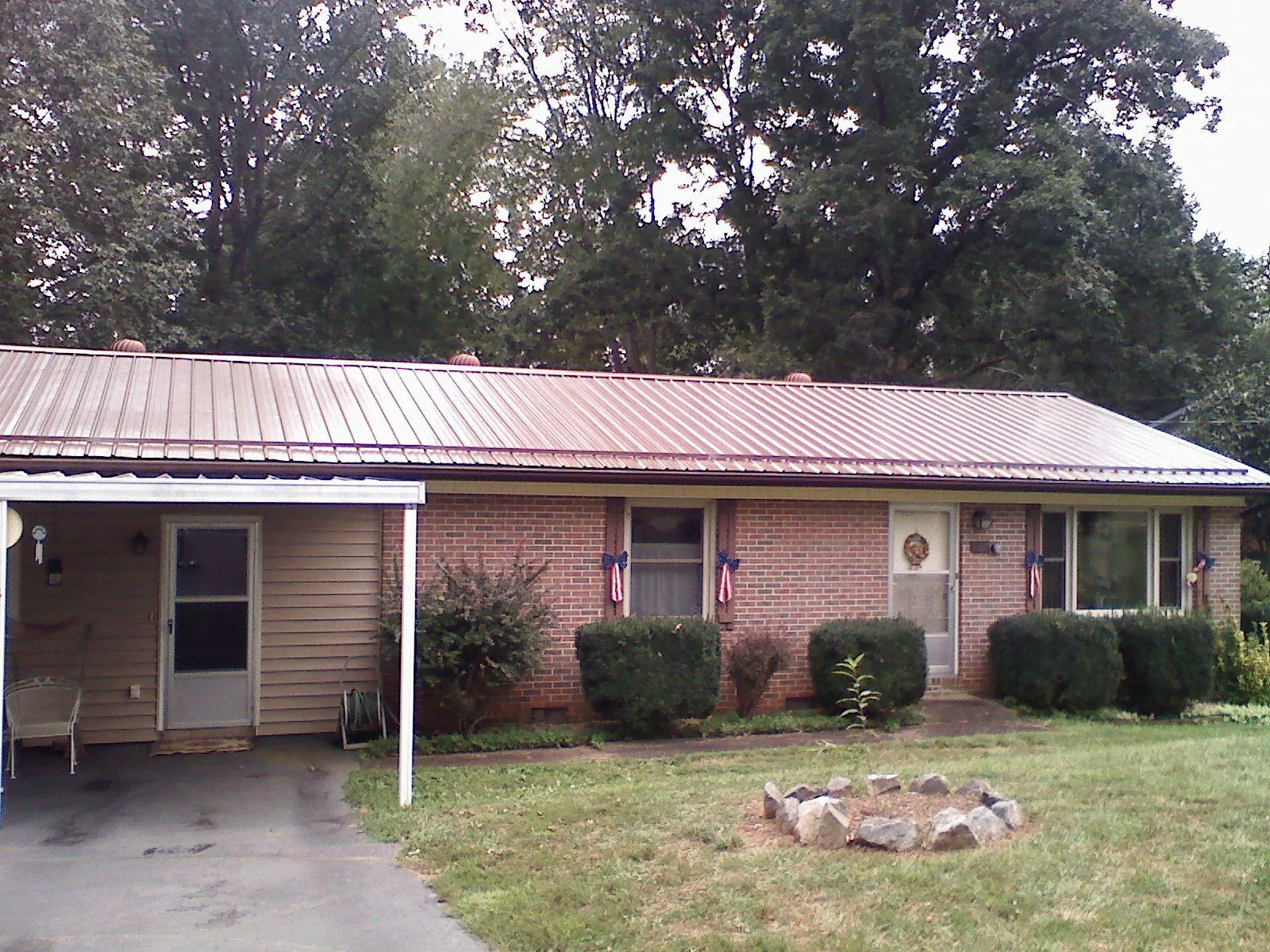 Bronze metal roof and carport on a brick ranch home — Roof Repair work by our crew in Durhamville