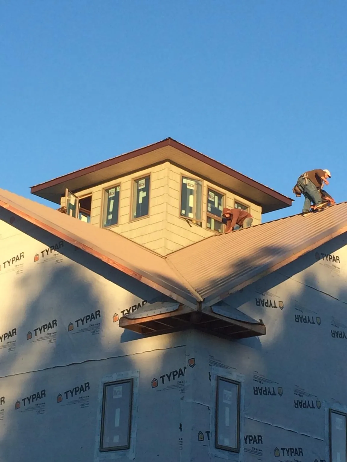 Roofers working around a rooftop cupola on a new metal roof at sunset — Roof Waterproofing in Durhamville by Roofing Brothers